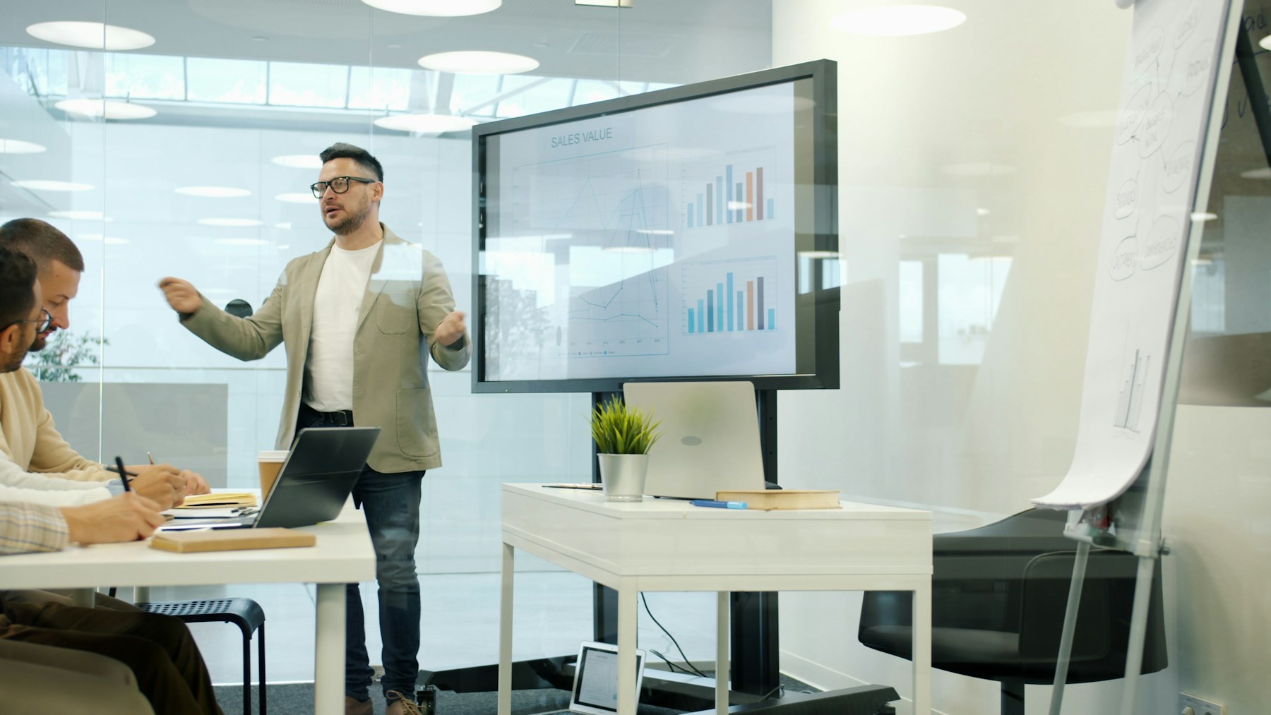 Presenter explaining charts on a large meeting-room display